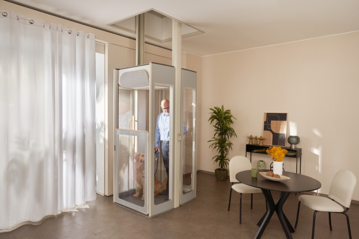 Un hombre de mediana edad con su perro en el ascensor doméstico Uplifts de Stannah.