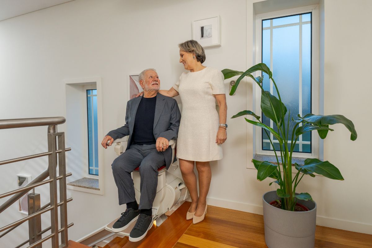  Pareja feliz en casa, con una silla salvaescaleras Stannah 